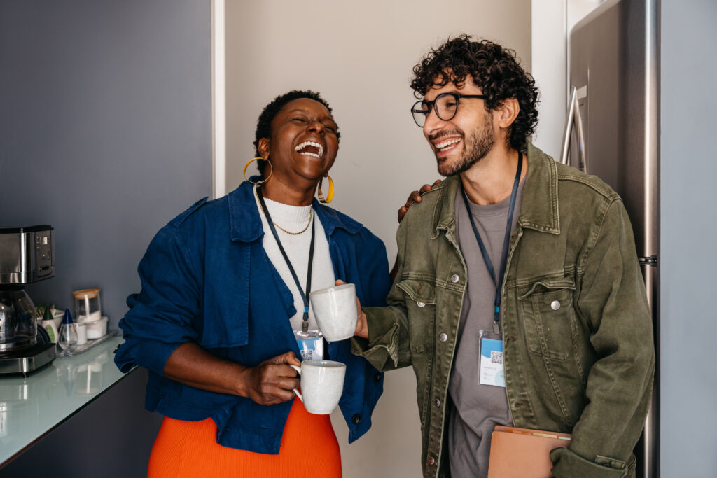Employees Dallas TX - Office employees laughing together on a coffee break. Colleagues building friendship in a professional environment.